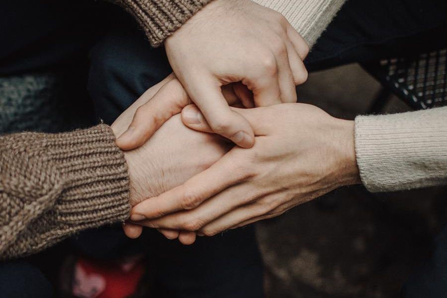 two people holding hands in a caring way, indoors